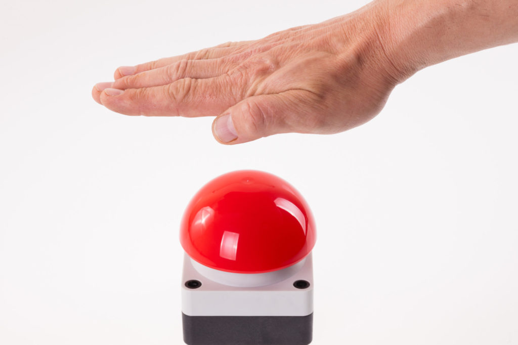 Hand pushing a red buzzer