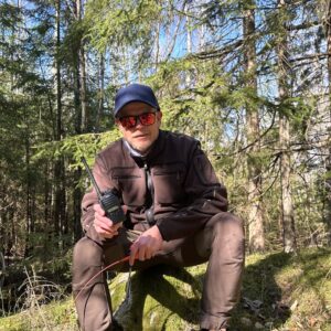 Mann som sitter i skogen og holder to sikringsradioer